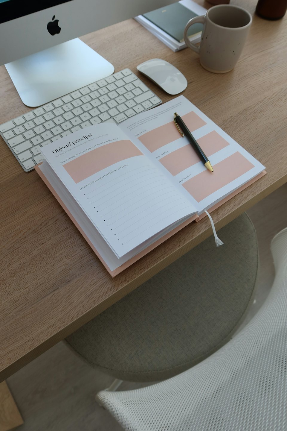 Een open agenda en pen liggen op een houten bureau.