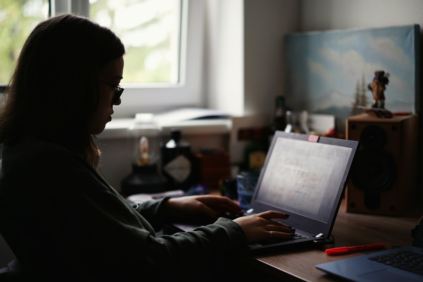 Persoon die op een laptop werkt aan een houten bureau.